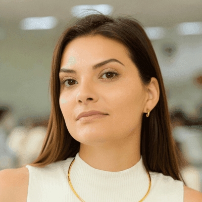 a woman wearing a white top and a gold necklace