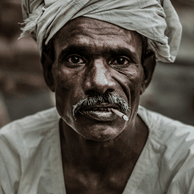 man wearing gray turban smoking cigarette in closeup photography