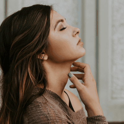 woman in brown long-sleeved top standing beside wall