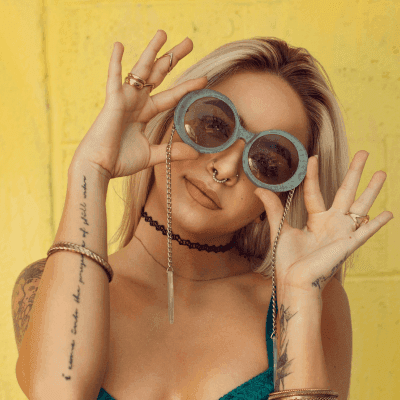 woman in blue bralette holding sunglasses putting on her eyes